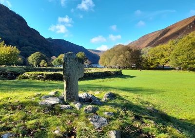 Stone cross against a backdrop of a blue sky and mountains